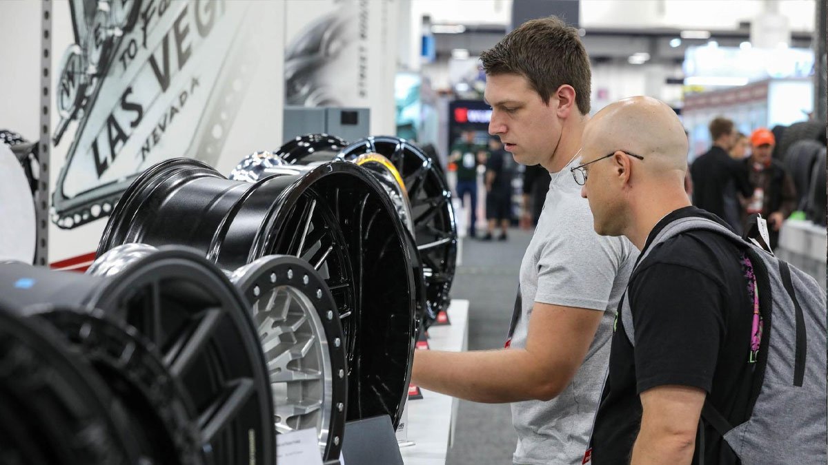 Dos asistentes revisando rines personalizados en exhibición en el SEMA Show de Las Vegas